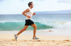 Fitness sports runner man jogging on beach. Handsome young fit s