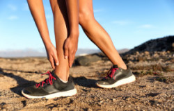 Runner woman with hurt ankles in pain during marathon. Athlete w